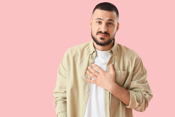 Apologetic young man on pink background