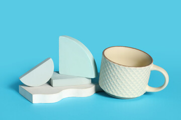 Decorative podiums with white ceramic cup on blue background