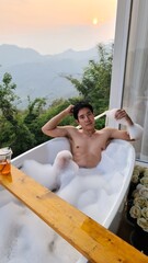 Handsome Man Relaxing in Bubble Bath with Stunning Mountain Sunset View