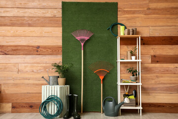 Shelving unit, houseplants and gardening tools near wooden wall in barn