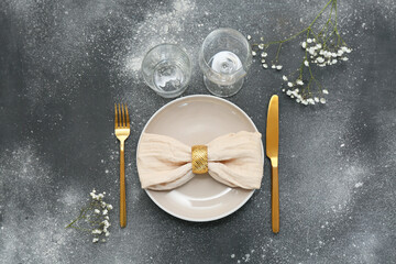 Beautiful table setting with golden cutlery and gypsophila flowers on dark background