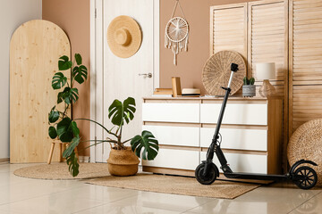 Interior of living room with electric scooter, commode, folding screen, wooden board and houseplant