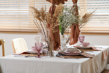 Elegant table setting with beautiful flowers, pampas grass and willow branches in stylish dining...
