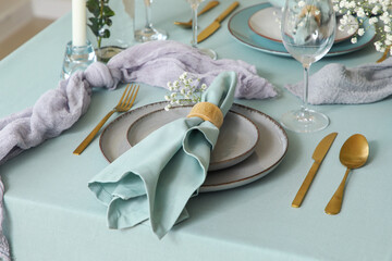 Elegant table setting with beautiful flowers, golden cutlery and folded napkin in restaurant