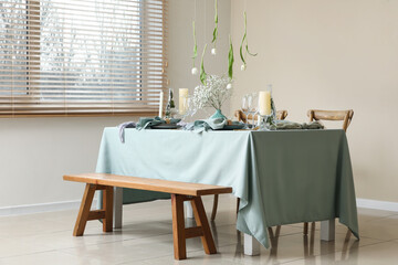 Elegant table setting with beautiful flowers, candles and hanging tulips in stylish dining room