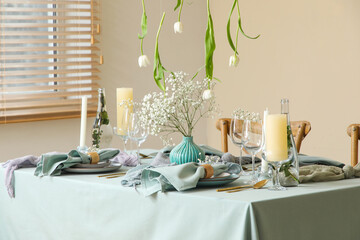 Elegant table setting with beautiful flowers, candles and hanging tulips in stylish dining room