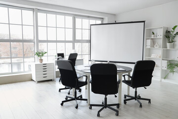 Interior of conference hall with blank projector screen and table