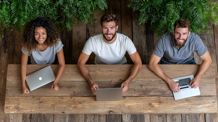 Three people working together on laptops at rustic table