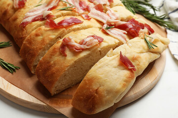 Slices of delicious focaccia bread with bacon and rosemary on white table, closeup