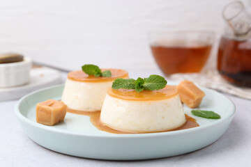Tasty puddings with caramel sauce served on white table, closeup