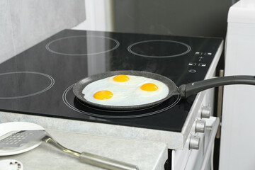 Cooking tasty eggs on frying pan in kitchen, closeup