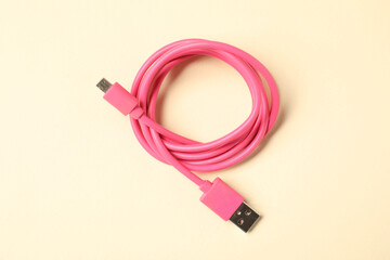 One USB charge cable on beige background, top view