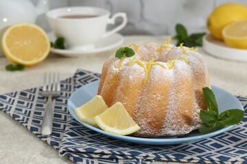 Delicious cake with lemon zest, powdered sugar and mint on light textured table, closeup