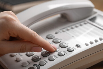 Woman dialing number on landline telephone, closeup