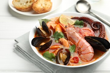 Delicious seafood soup served on white wooden table, closeup