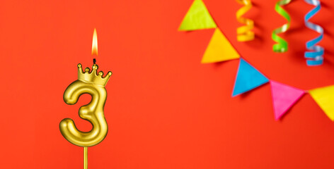 Number 3 birthday candle on an orange background with pennants