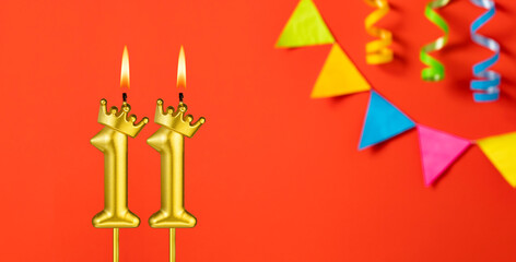 Number 11 candle - Birthday celebration on an orange background with pennants