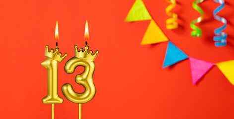 Number 13 candle - Birthday celebration on an orange background with pennants
