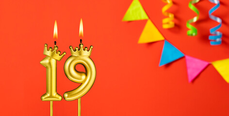 Number 19 candle - Birthday celebration on an orange background with pennants