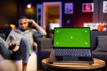 African american man browses mobile phone next to mockup copy space while he relaxes on a bean bag,...