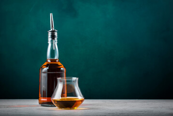 French Brandy in glass with bottle on dark green background