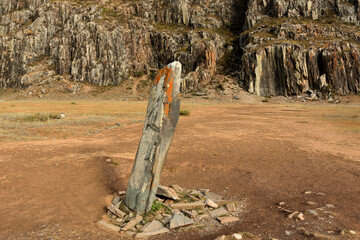 An ancient ritual stone with a carved human face stands on the edge of the steppe at the foot of...