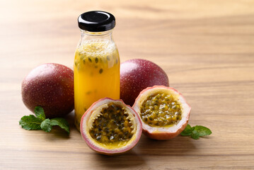 Bottle of passion fruit juice with fresh passion fruit on wooden background, Healthy drink