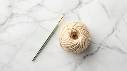  A single crochet hook and a small skein of yarn centered on a white marble surface