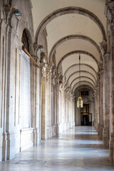 A long hallway with beautiful arches and sturdy columns exists