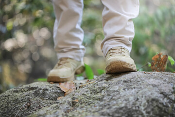 Hiker with hiking boots standing on rock mountain nature background. Hiker men's hiking living healthy active lifestyle.
