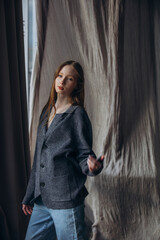 Obraz premium Beautiful blonde model, young girl, teenager in the studio in a jacket and jeans against the background of fluttering fabrics