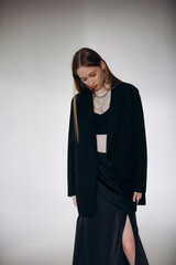 Fototapeta premium Beautiful blonde model, young girl, teenager in the studio in a black jacket on a white cyclorama