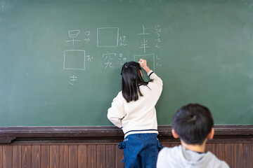 黒板に回答を書く小学生 © milatas