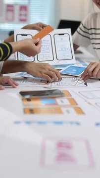 Ui/ux designers team creating mobile application design using paper prototypes, enhancing the user experience and interface design.