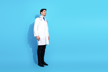 Young male doctor in a white lab coat smiling against a vibrant blue background showcasing positivity and professionalism