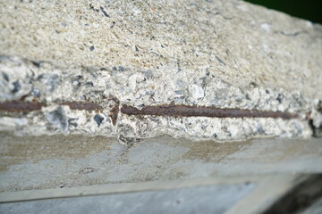 Close-up of exposed and corroded steel reinforcement in concrete due to rust jacking, showing signs of deterioration and structural damage.