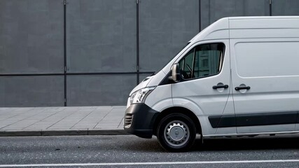 White delivery van driving along a city street, passing a modern building with large windows, representing urban logistics and e commerce transportation