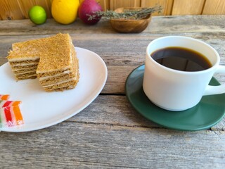 white coffee cup on an old wooden table next to a cake. High quality photos