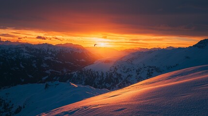 Sunset over snow-covered mountains with paragliders soaring in the distance during winter