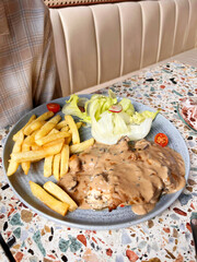 Grilled chicken breast served with mushroom sauce and salad.