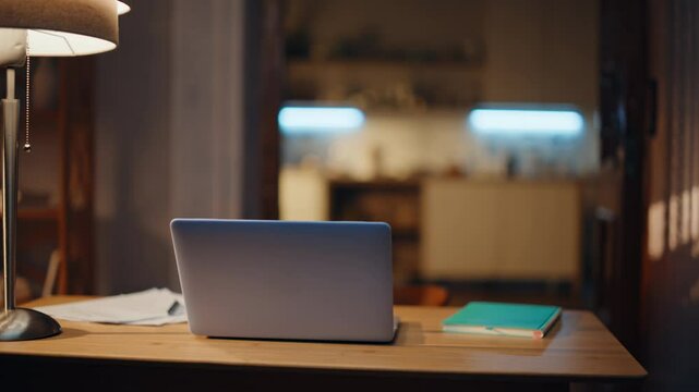 Laptop standing desk empty apartment room at lamp light closeup. Open computer