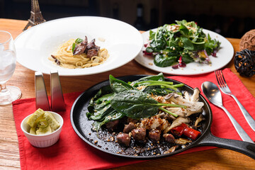 Beef, oil pasta and salad on a grill pan
