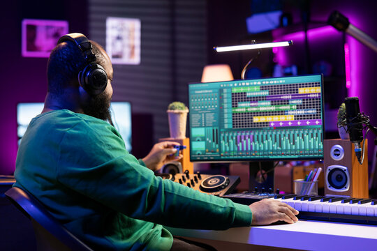 Musical engineer producing new tracks with an usb stick in home studio, editing songs from old audio files. Young sound designer mixing and mastering his recordings, professional software.