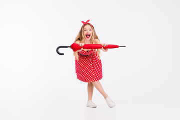 Joyful blonde woman in red polka dot dress posing with umbrella, evoking retro nostalgia and glamour against a clean white background