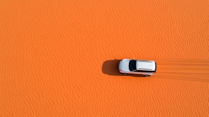 Fototapeta premium Majestic aerial view of a white car trailing through vibrant orange sand dunes, showcasing colorful desert landscapes and adventure.