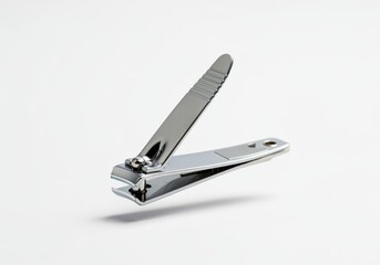 A silver nail clipper floating horizontally in mid-air against a solid white background