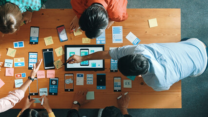 Top view of software developer team looking Ux Ui design for mobile phone interface from tablet...