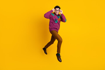 Stylish Young Man in Retro Sweater Posing in Excited Expression over Vibrant Yellow Background with a Trendy and Energetic Gesture