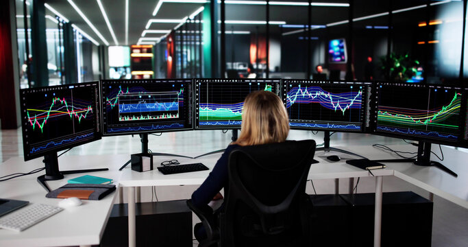 Young Female Stock Market Analyst Reviews Multiple Computer