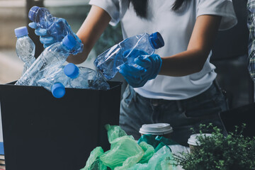 Close-up of female hands from a family collecting plastic waste and bottles from the ground. They...